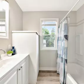 A white bathroom with a window and a white tub.