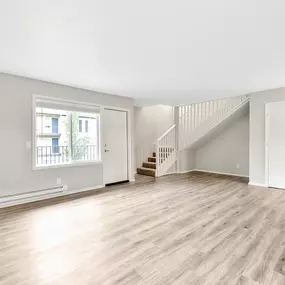 A spacious room with wooden flooring and a staircase.