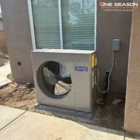 A newly installed American Standard outdoor AC unit sits beside a residential home, professionally placed by One Season Heating & Air Conditioning.