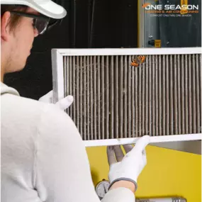 A technician inspects a heavily clogged air filter, highlighting the importance of regular HVAC maintenance for indoor air quality.