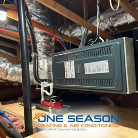 A One Season Heating & Air Conditioning attic installation features a central air handler unit connected to insulated ductwork, ensuring efficient climate control throughout the home.