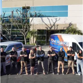 The team stands proudly in front of their office building and branded service vehicles, representing their commitment to professional HVAC services.