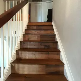 This image showcases a set of beautifully crafted wooden stairs, blending rich brown treads with crisp white risers and a white railing. The warm tones of the wood create an inviting and elegant ascent.