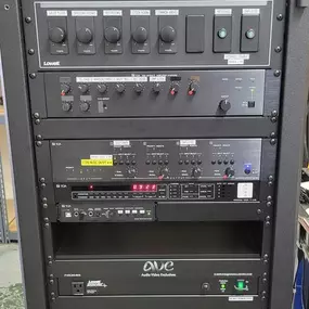 A rack of professional audio-video equipment is neatly organized, featuring various components with knobs, buttons, and digital displays. An 