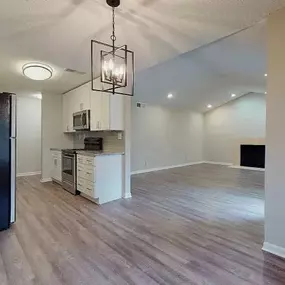 A kitchen area with a black refrigerator and a wooden floor.