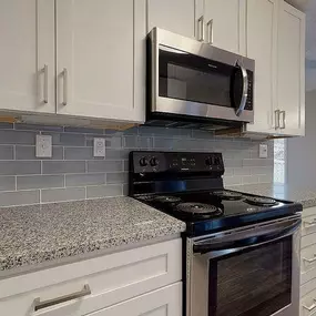 A kitchen with a black stove top oven and a microwave above it.