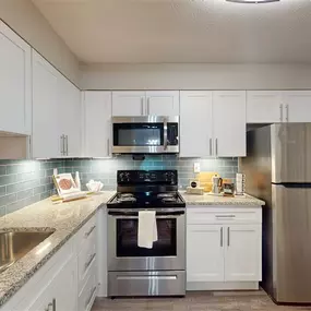 A kitchen with a stainless steel refrigerator, sink, and stove.