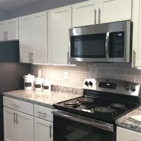 A kitchen with a black stove top oven and a black microwave above it.