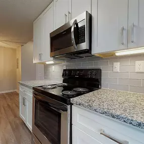 A kitchen with a black microwave above the stove.