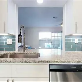 A kitchen with a stainless steel dishwasher and white cabinets.