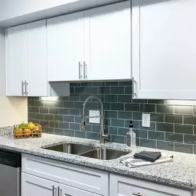 A kitchen with white cabinets and a granite countertop.