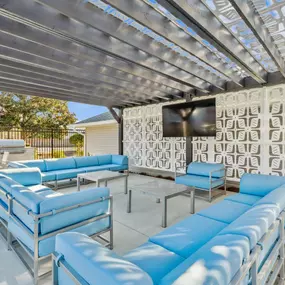 a lounge area with blue couches and chairs and a tv