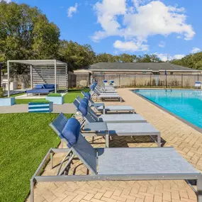 a resort style pool with blue and gray lounge chairs