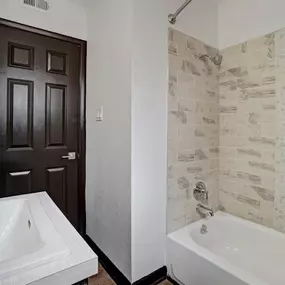 A bathroom with a tub and a sink and a door