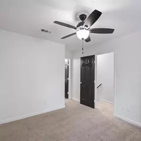 A room with a ceiling fan and carpeted floor.