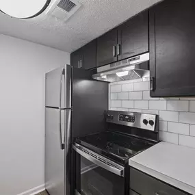 A kitchen with black cabinets and a stove top oven.