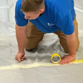 Team member from First Response Restoration of RGV securing a tarp with yellow tape during a water damage restoration project in the Rio Grande Valley. Wearing a branded blue uniform, this image highlights our 24/7 emergency response and expertise in flood cleanup and property restoration in McAllen, Brownsville, and surrounding areas. IICRC certified (#70221362). Call (956) 305-4229 for immediate service.