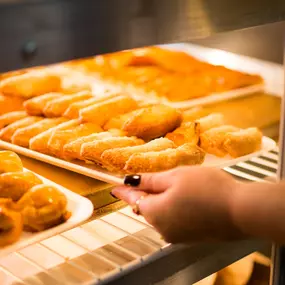 A person placing a tray of croquettes in the display.