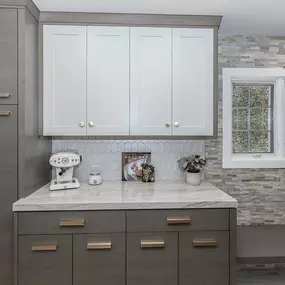 A professional is mulching an overgrown wooded area with a yellow Vermeer S925TX mini skid steer. Trees stand in the background, and the ground is covered in wood chips.