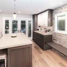 A professional is mulching an overgrown wooded area with a yellow Vermeer S925TX mini skid steer. Trees stand in the background, and the ground is covered in wood chips.