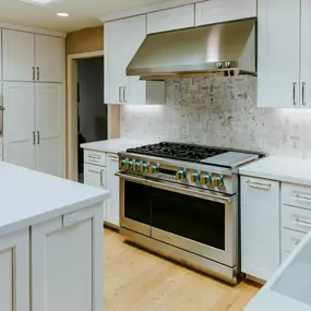Two individuals are setting out animal traps on a grassy area near a house. One is placing bait in a trap, while the other observes. An air conditioning unit is in the background.
