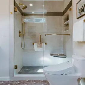 A professional is mulching an overgrown wooded area with a yellow Vermeer S925TX mini skid steer. Trees stand in the background, and the ground is covered in wood chips.