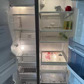 This image shows a very dirty refrigerator with both the freezer and fridge sections open. Spills, crumbs, and general grime cover the shelves and drawers, indicating a significant need for a thorough cleaning service.