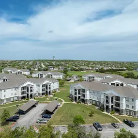 Aerial view of Lakeline Apartments highlighting the full property layout, surrounding greenery, nearby street parking, and proximity to neighborhood amenities in Leander, TX.
