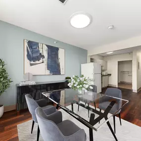 A modern dining room with a glass table and grey chairs