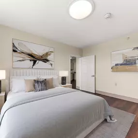 A bedroom with a large bed and a painting of a dragonfly on the wall