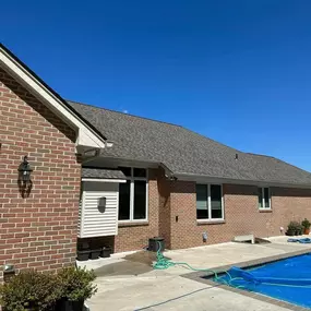 An exterior shot of a house with a newly built outdoor kitchen. It features a stainless steel grill and appliances, along with cabinets covered in blue protective film.