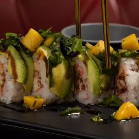 (SOY PAPER WRAP) Soft-shell crab tempura with baked krab inside, layered avocado outside, drizzled with eel sauce, topped with diced mango, jalapeño, spring mix and sweet chili sauce.