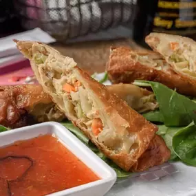 Two crispy fried pork and vegetable egg rolls with sweet chili sauce.