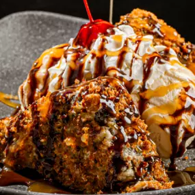 A towering stack of golden-fried brownieslices, vanilla ice cream, whipped cream,chocolate and caramel swirls—with a cherry on top. Epic.