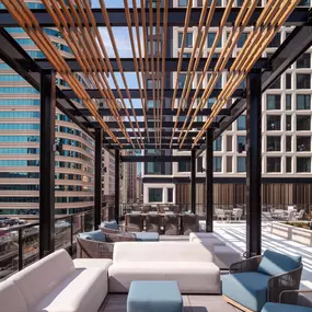 A wooden pergola over a patio with white and blue couches