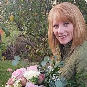 Christina smiling holding a wedding bouquet she designed at her flower studio in Hagerstown Maryland.