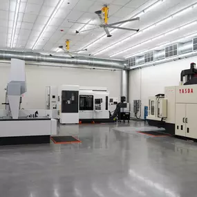 A wide-angle interior photo of the Methods Machine Tools showroom in Corona, California, featuring live CNC machine displays and demonstration setups.