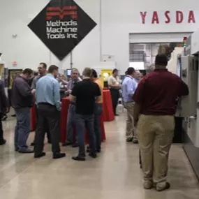 Industry professionals gather at a convention inside Methods Machine Tools Inc. in Wixom, Michigan, surrounded by advanced CNC machinery and partner brand displays.