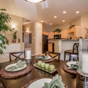 A dining table set with green apples and candles.