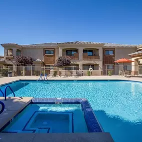 A large swimming pool in front of a building with a clear blue sky.