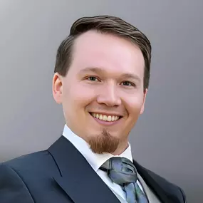 Professionelles Porträt von Robert Skawinski im Anzug mit freundlichem Lächeln.