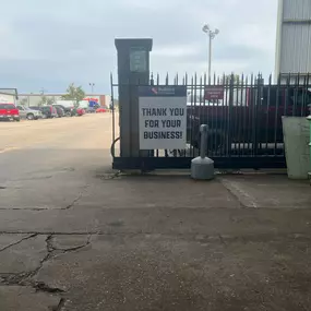 A gated exit at a Builders FirstSource facility with a sign that reads 