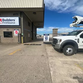 A receiving area at a Builders FirstSource facility with a large company sign mounted above the entrance. A 