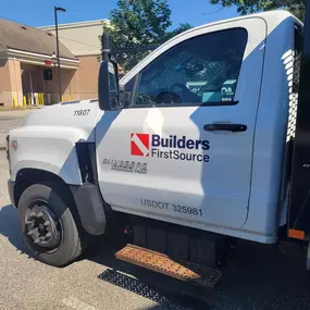 Builders FirstSource delivery truck with white cab.