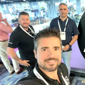 Photo of Revest Construction team members smiling at a professional event or trade show, showcasing industry involvement.