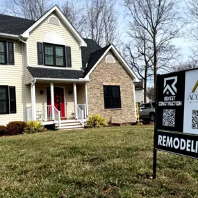 Photo of a residential job site with Revest Construction yard signs placed outside, indicating an active remodeling project.
