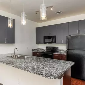 A kitchen with granite countertops and black appliances.