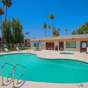 A large swimming pool surrounded by palm trees and lounge chairs.