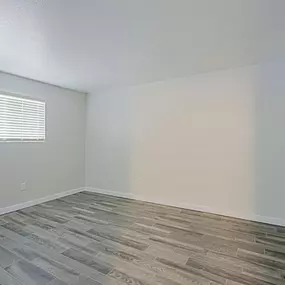 A room with a wooden floor and a window with blinds.