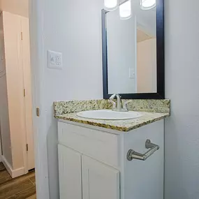 A bathroom vanity with a marble top and a mirror above it.